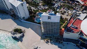 Luftaufnahme eines Küstenhotels mit Strand, Pool und modernen Gebäuden.