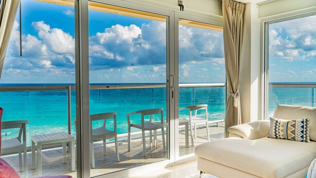 Ein Balkon mit Blick auf das Meer, eine weiße Couch und einige Stühle.