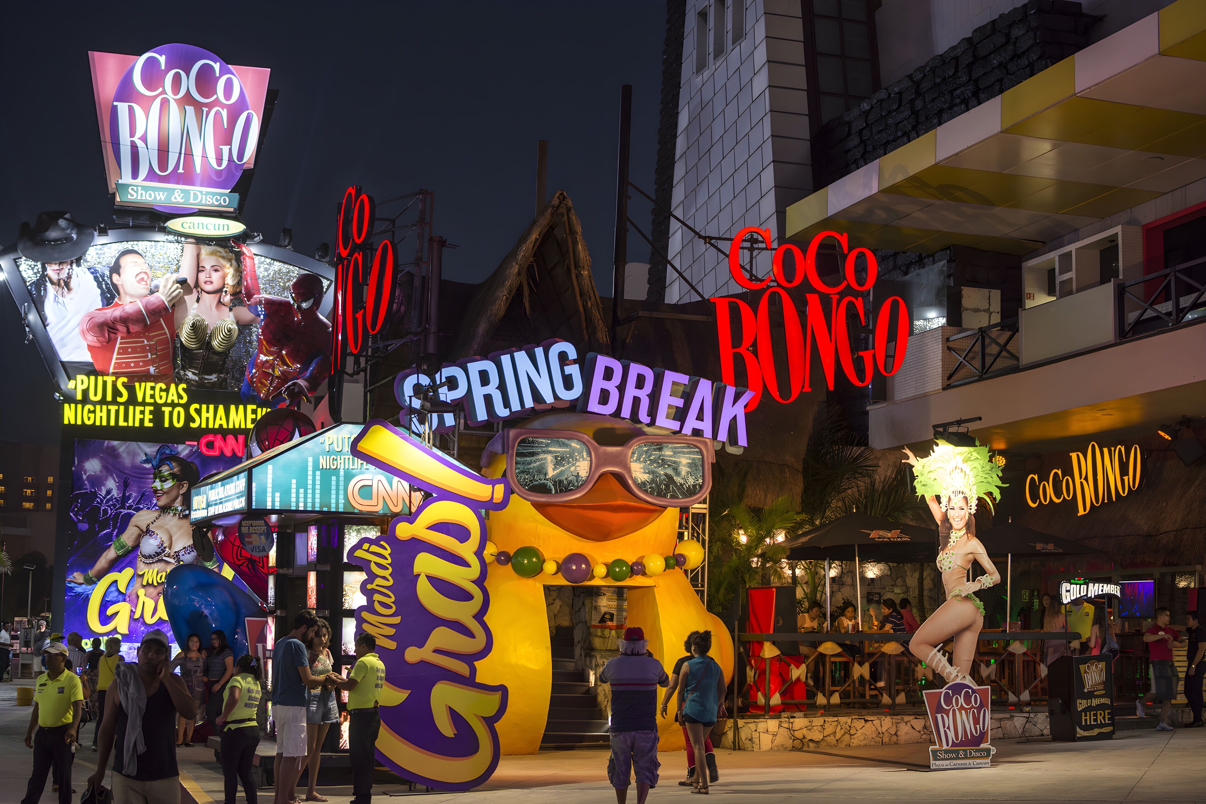 Eine lebhafte Straßenszene mit einer großen aufblasbaren Figur und Neonreklamen für Coco Bongo.
