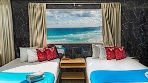 Ein Hotelzimmer mit zwei Betten, einem Holznachttisch, Meerblick und einer Marmorwand.