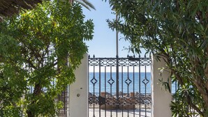 A gated entrance with a view of the sea, surrounded by lush greenery and a clear sky. - Skol Sea Views Apartments (Marbella)
