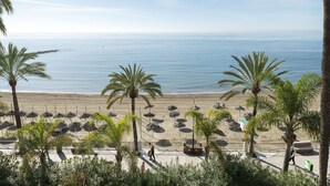 A beach with palm trees, a sandy shore, and a clear view of the sea. - Skol Sea Views Apartments (Marbella)