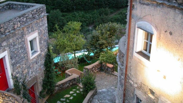 A stone building with a small courtyard, a pool, and a view of a forested area. - Stunning Medieval Mountain Retreat With Pool (Castelbianco)