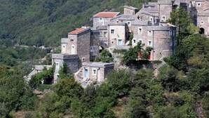 A cluster of stone buildings with red-tiled roofs, surrounded by dense greenery and hills in the background. - Apartment Sleeps 4 With Garden Terrace (Castelbianco)
