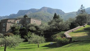 A stone building with multiple windows, surrounded by lush greenery and trees. - Apartment Sleeps 4 With Garden Terrace (Castelbianco)