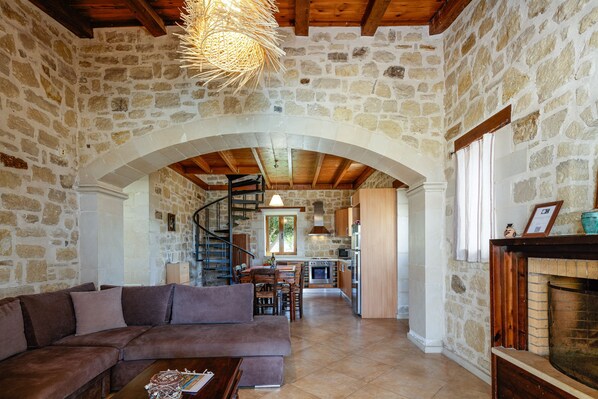 A stone-walled interior with a living area, kitchen, and staircase.