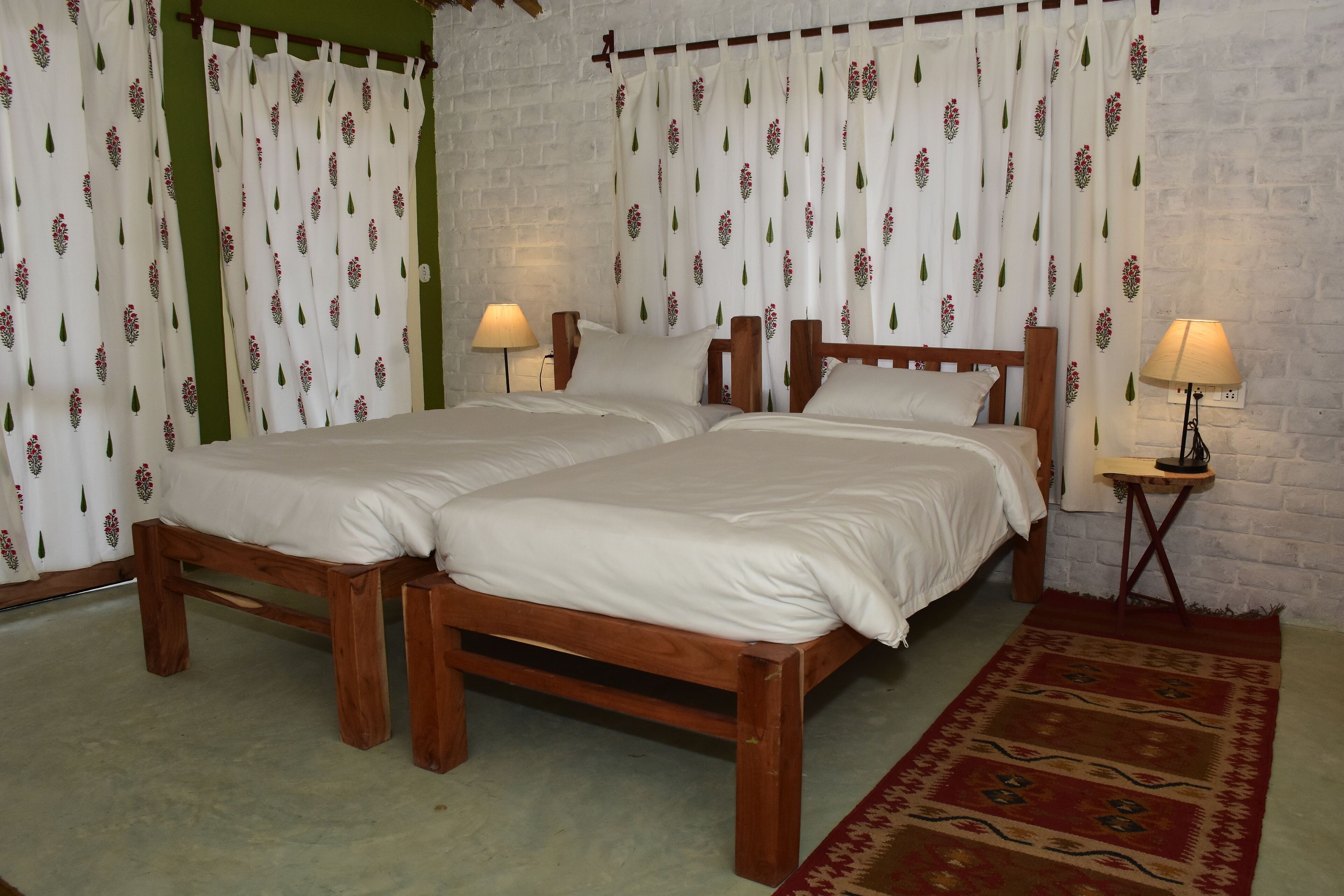 A double bed with a wooden frame and white bedding, two bedside tables with lamps, and a patterned rug on a carpeted floor.