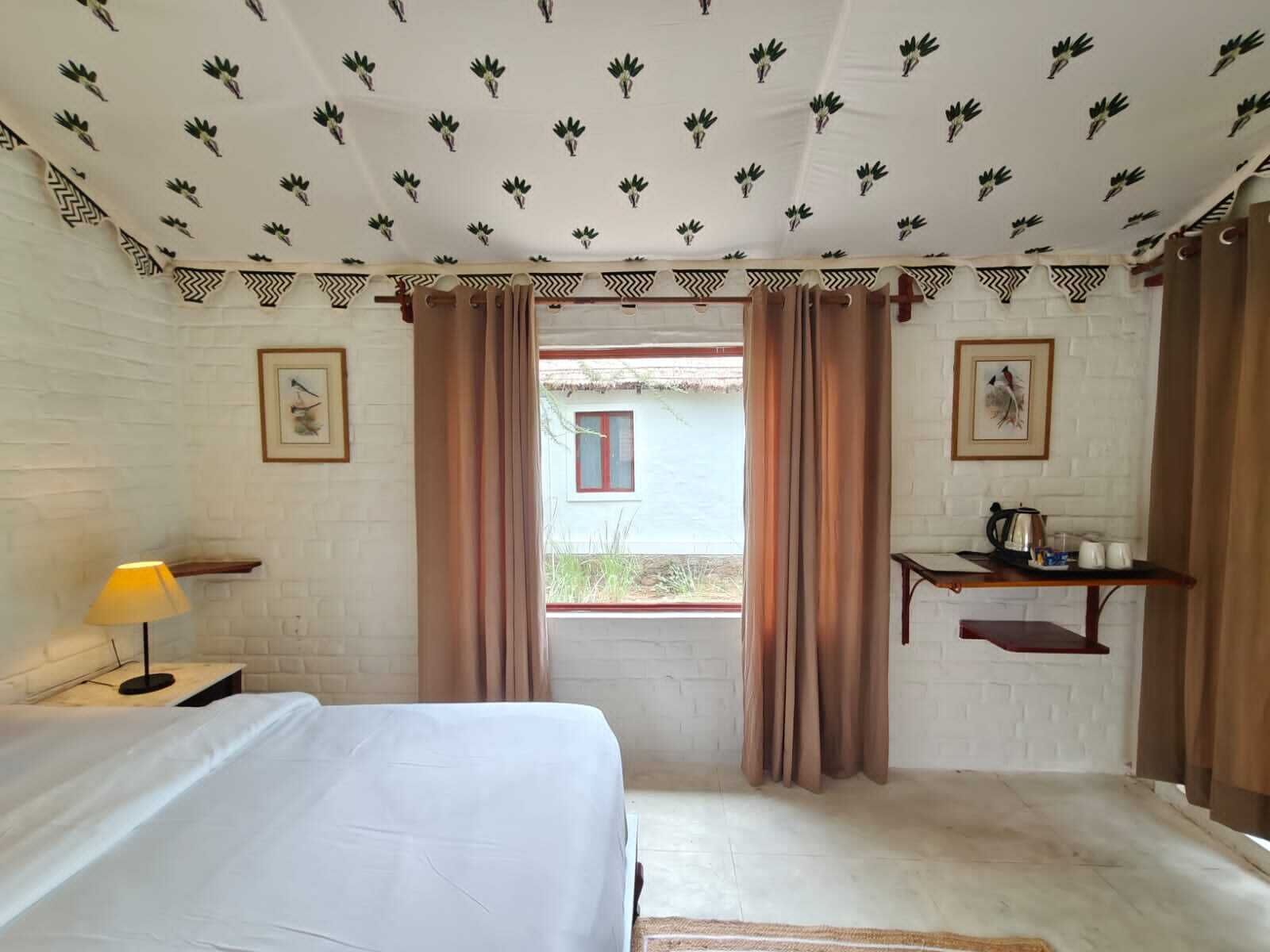 Una habitación con una cama, un escritorio, una lámpara y una ventana con cortinas.