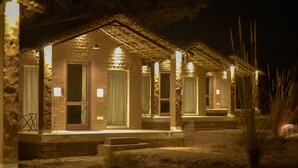 A stone building with multiple rooms, each with a door and windows, and a covered porch area. - Camp Land's End (Pushkar)