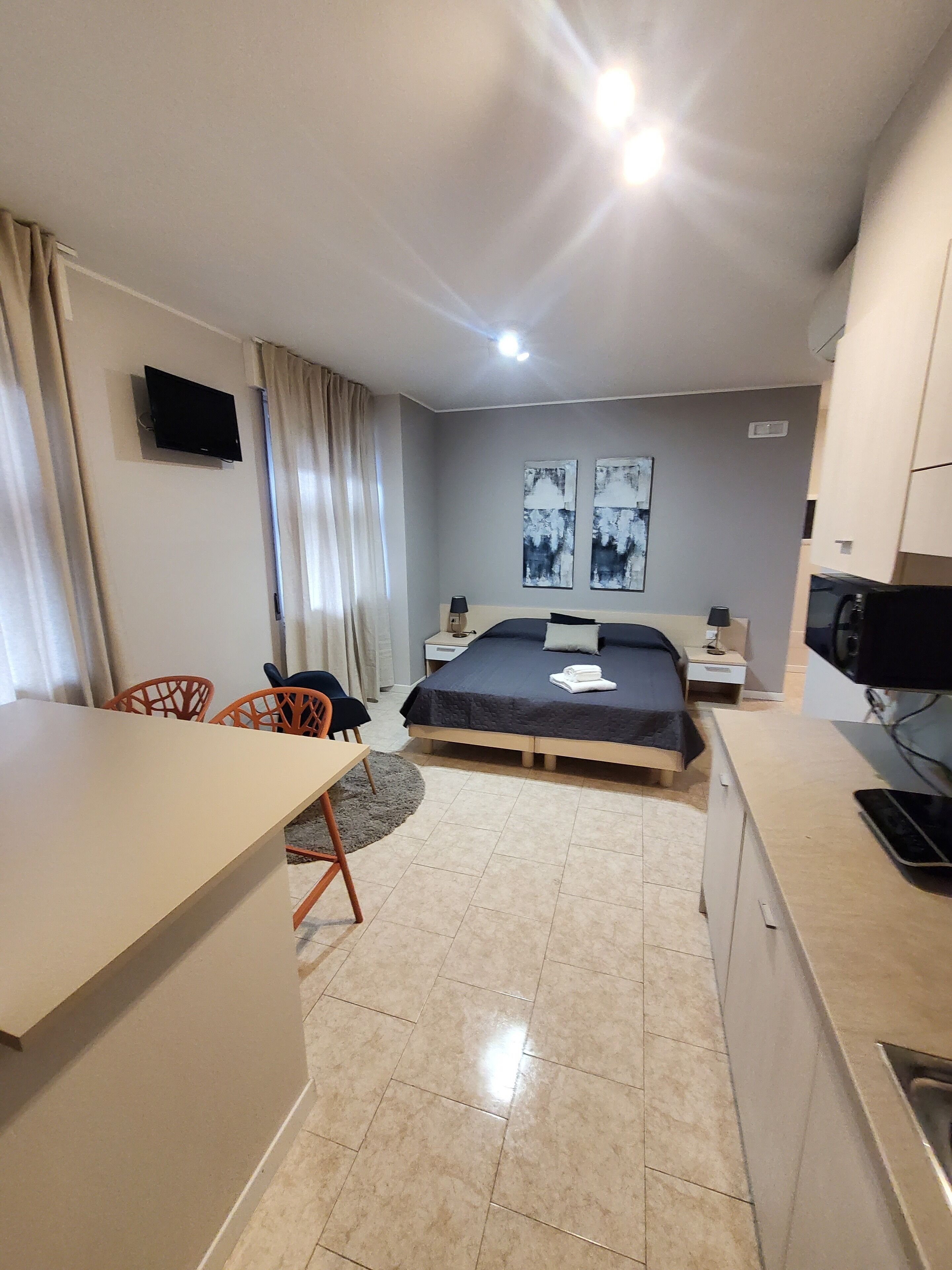 A modern hotel room with a bed, a desk, a chair, and a TV.