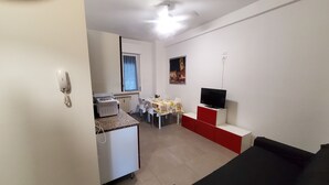 Um espaço compacto com cozinha compacta, área de refeições e televisão sobre suporte.