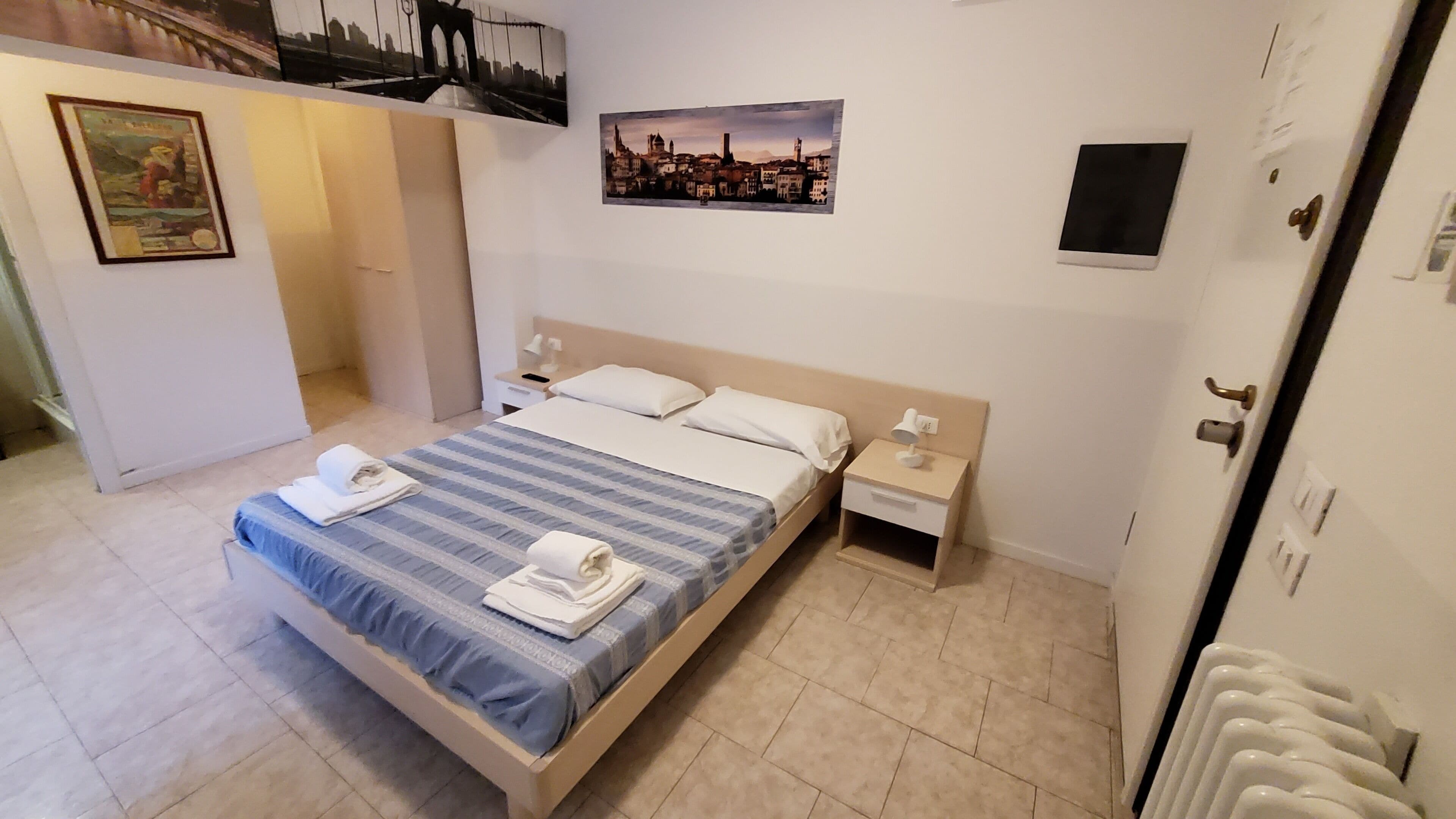 A neatly arranged bedroom with a bed, bedside tables, and a nightstand.