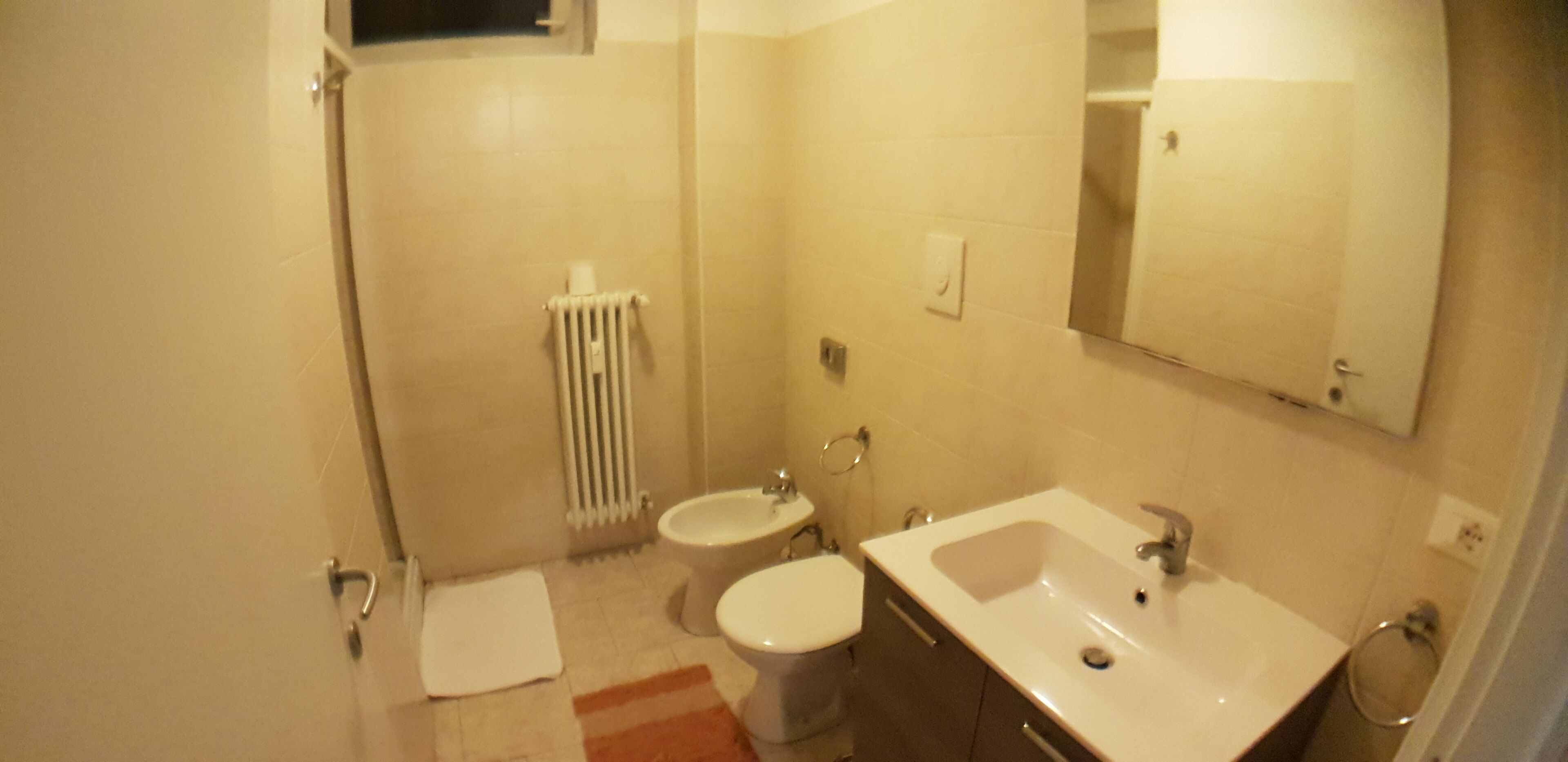 A bathroom with a toilet, bidet, sink, and mirror.