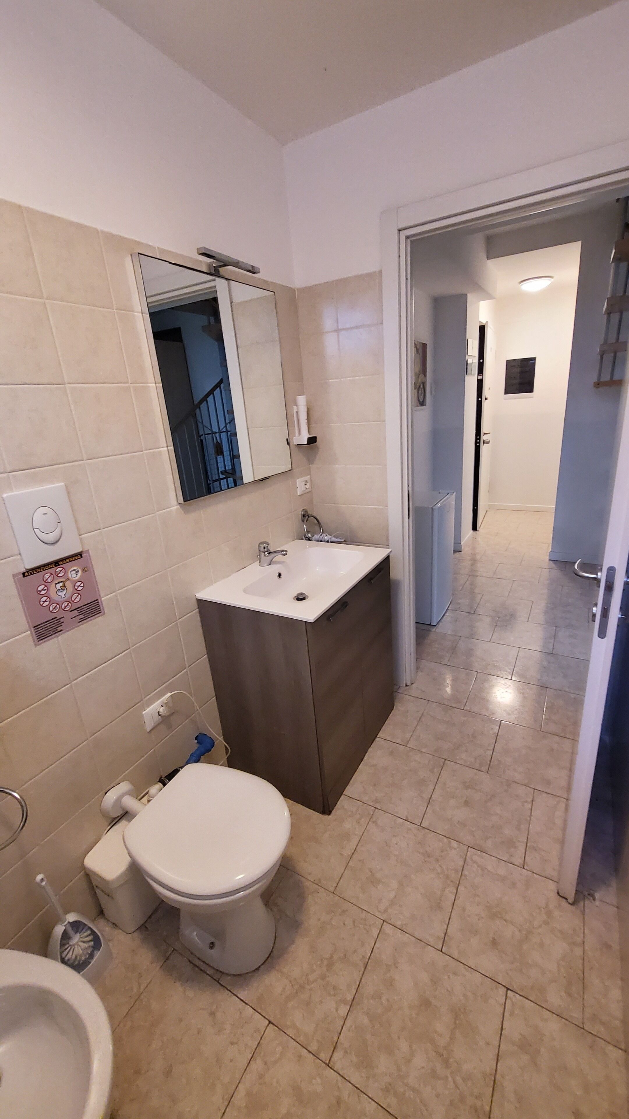 A bathroom with a toilet, sink, and mirror.