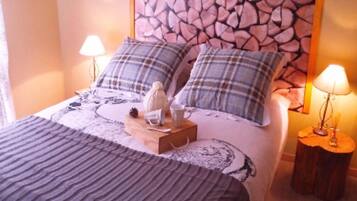 Una cama bien hecha con almohadones a cuadros, un cabecero decorativo y dos lámparas de noche.