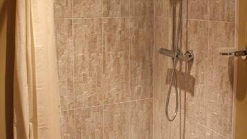Zona de ducha con ducha, cabezal de ducha y barra de apoyo.