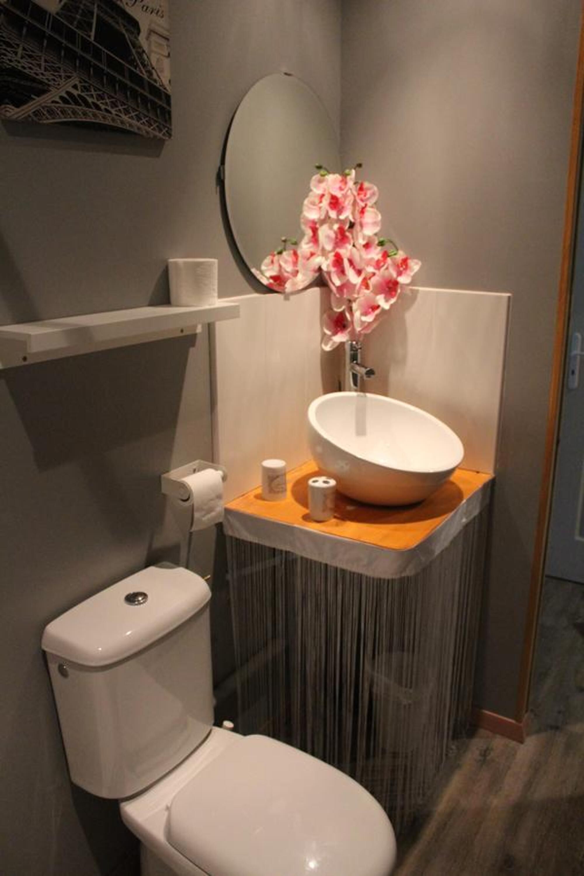 Un baño moderno con inodoro y lavamanos blancos, y un espejo sobre ellos.