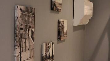 A room with a grey wall and a ceiling with a wooden trim. There are four framed pictures on the wall, depicting various architectural scenes.