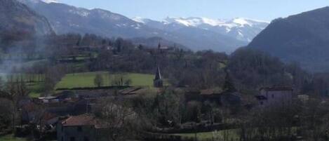 A mountainous village with houses and a church, surrounded by snow-capped peaks.