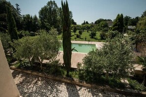 A pool surrounded by greenery and trees, with a clear sky. - La Villa Bella (Abzac)