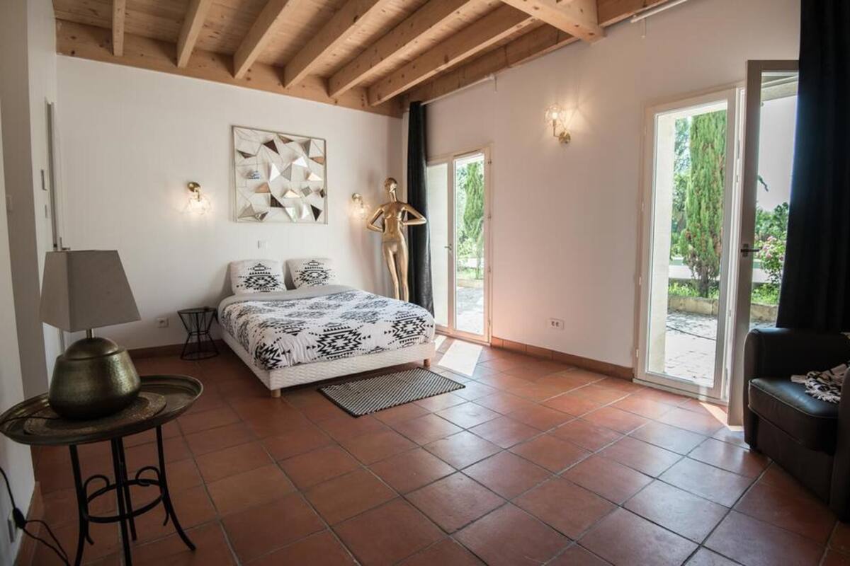 A bedroom with a bed, a lamp, a statue, and a view of the outdoors.