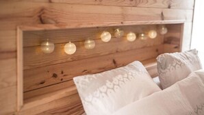 Een houten hoofdbord met lichtslingers en gekleurde kussens.