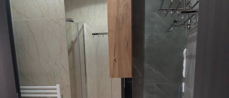 Un baño con lavamanos blanco, un espejo, un mueble de madera, un perchero y una lavadora.