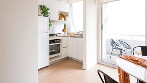 Una cocina moderna con armarios blancos, horno integrado y un comedor con mesa y sillas.