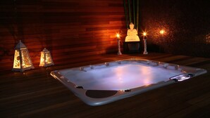 Un jacuzzi con piso de madera y una estatua de Buda al fondo.