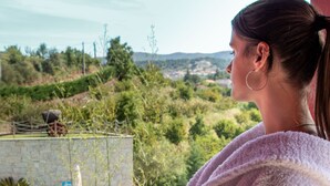 Una persona vestida con bata de baño junto a una piscina, con vistas a zonas verdes y colinas.