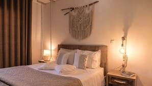 Una cama bien hecha con una colcha estampada, un adorno de macramé colgando en la pared y una lámpara de noche sobre una mesita de madera.
