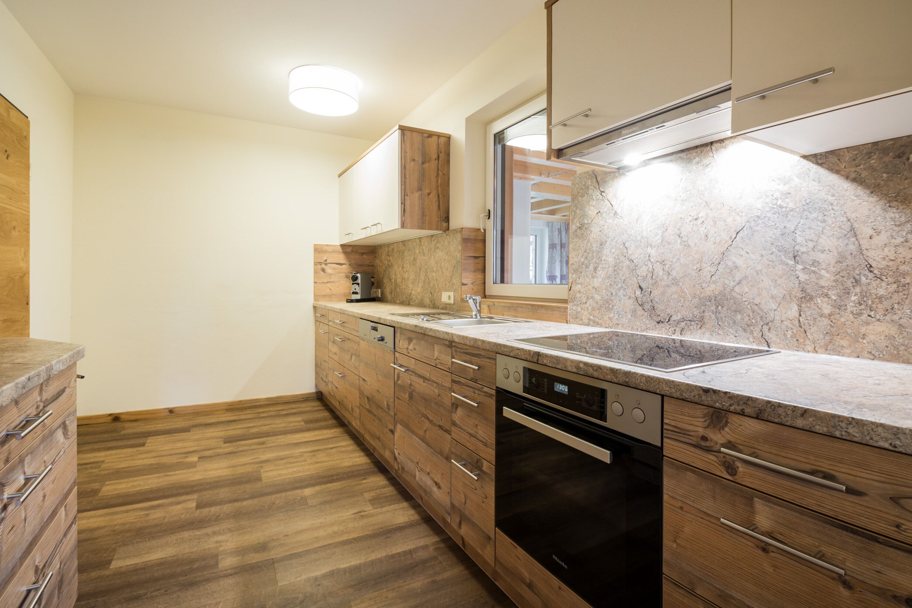Una cucina moderna con mobili in legno, un piano di lavoro in marmo e una lavastoviglie integrata.
