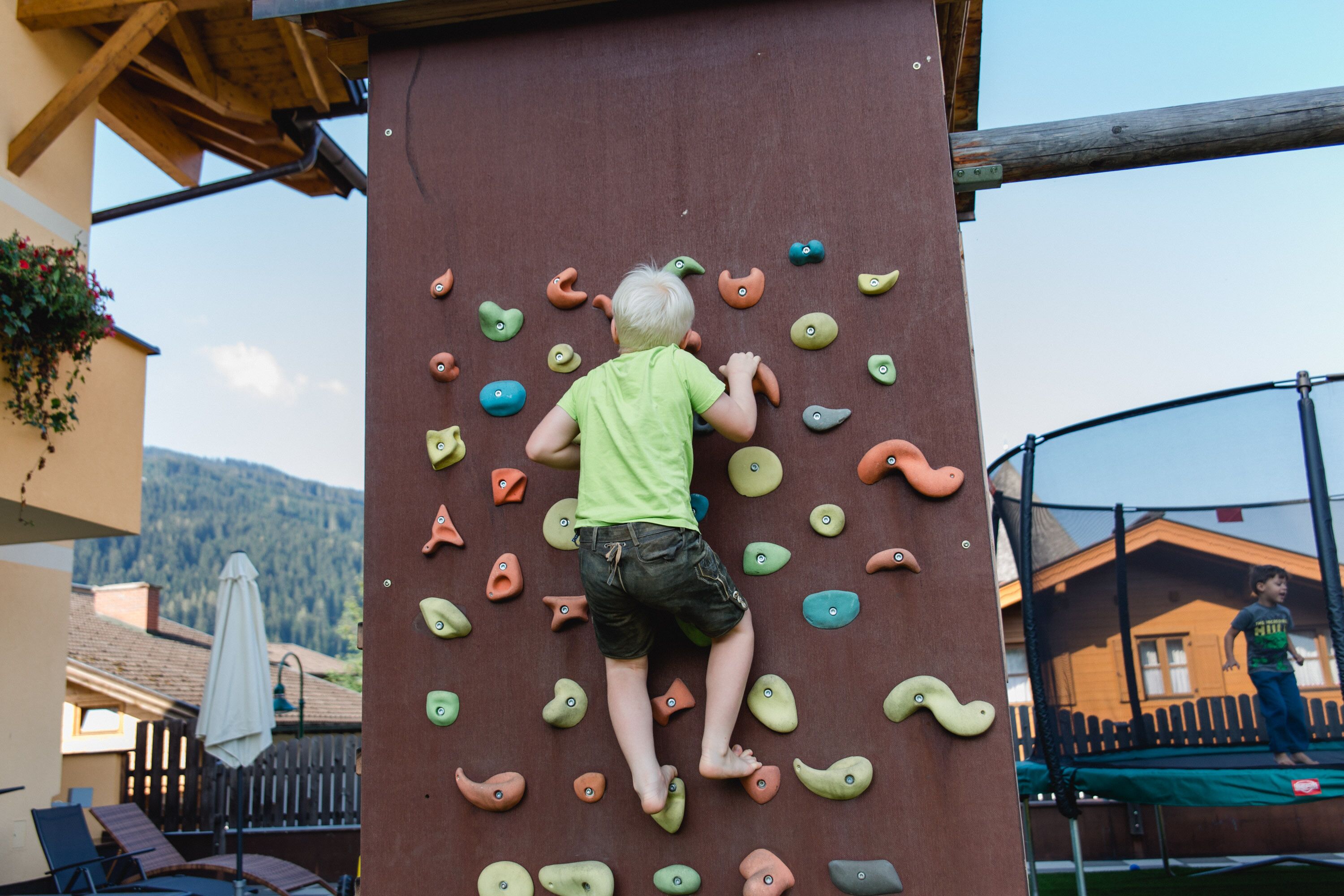 A child climbing a wooden climbing wall with various holds.