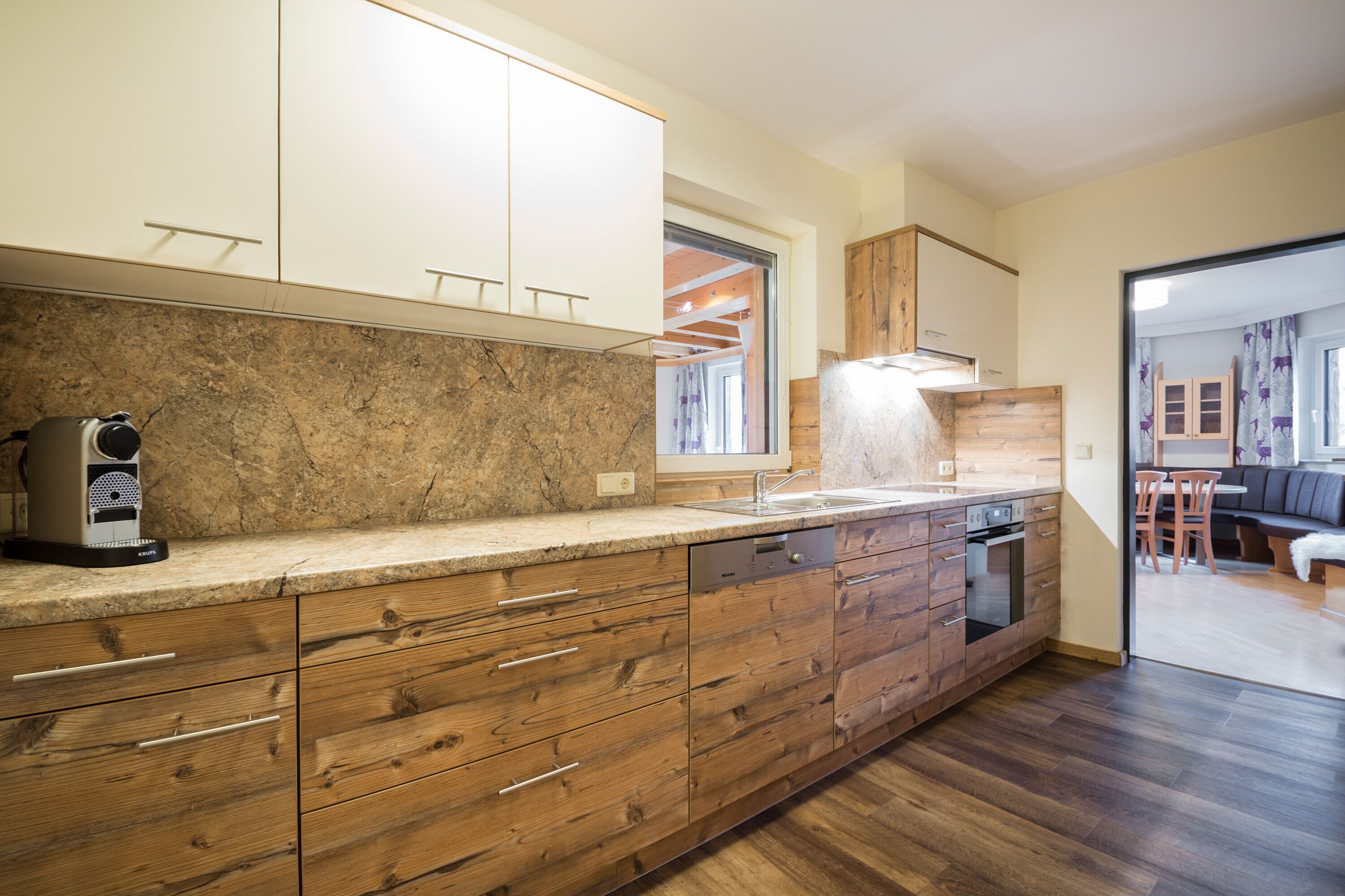 Una cocina moderna con armarios de madera, encimera de granito y horno empotrado.