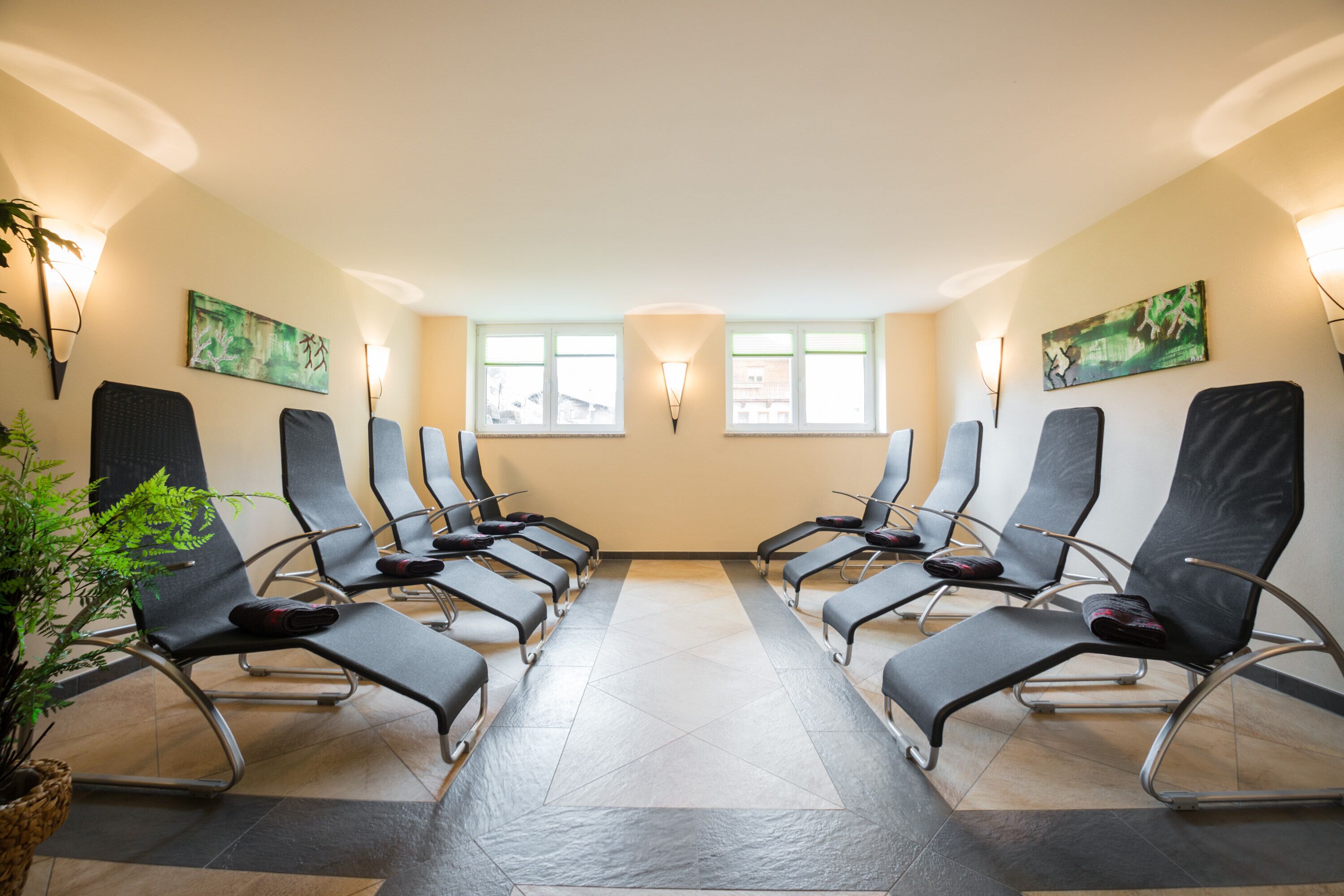 A waiting area with rows of chairs, a potted plant, and artwork on the walls.