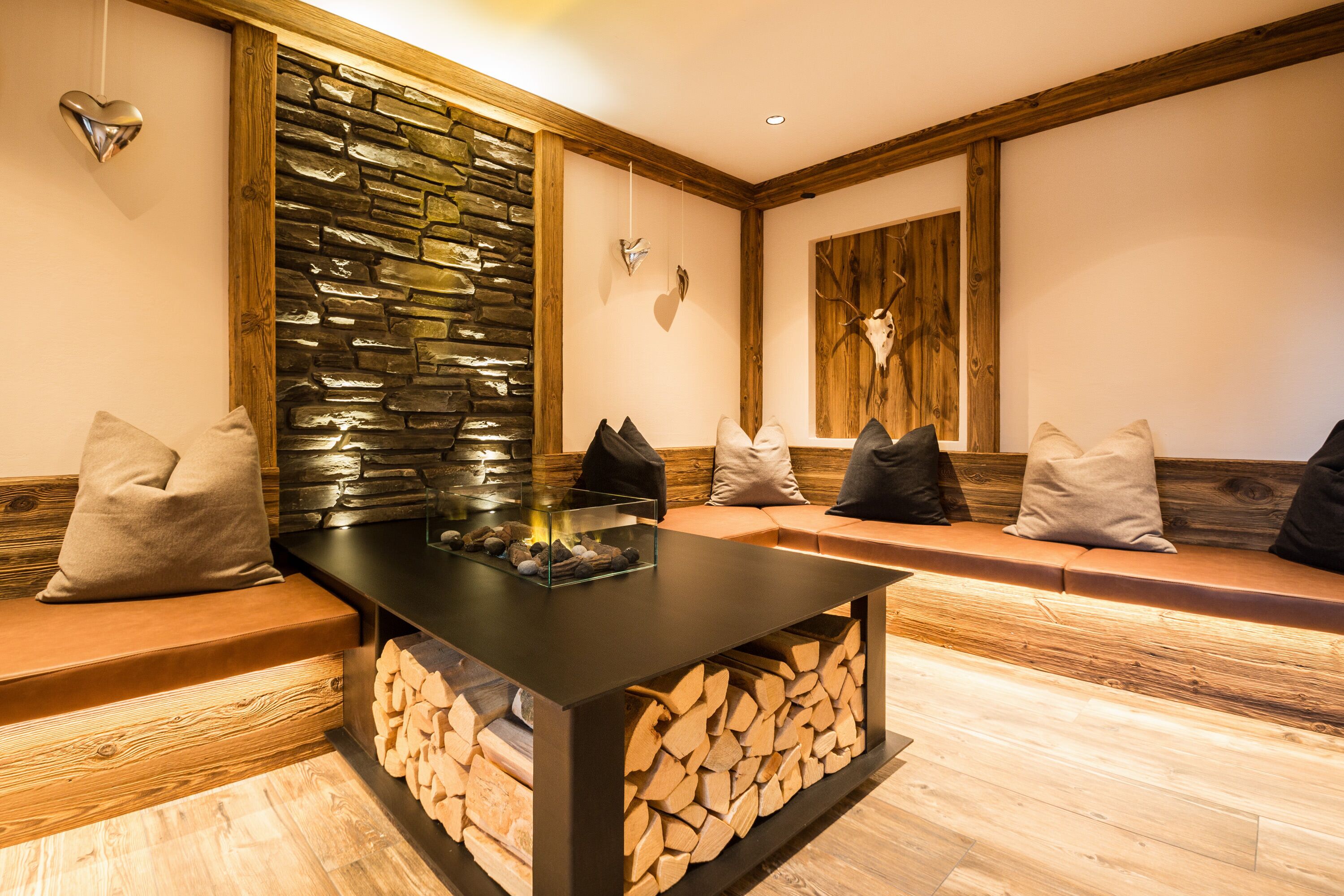 A cozy seating area with a stone wall, wooden beams, and a fireplace.