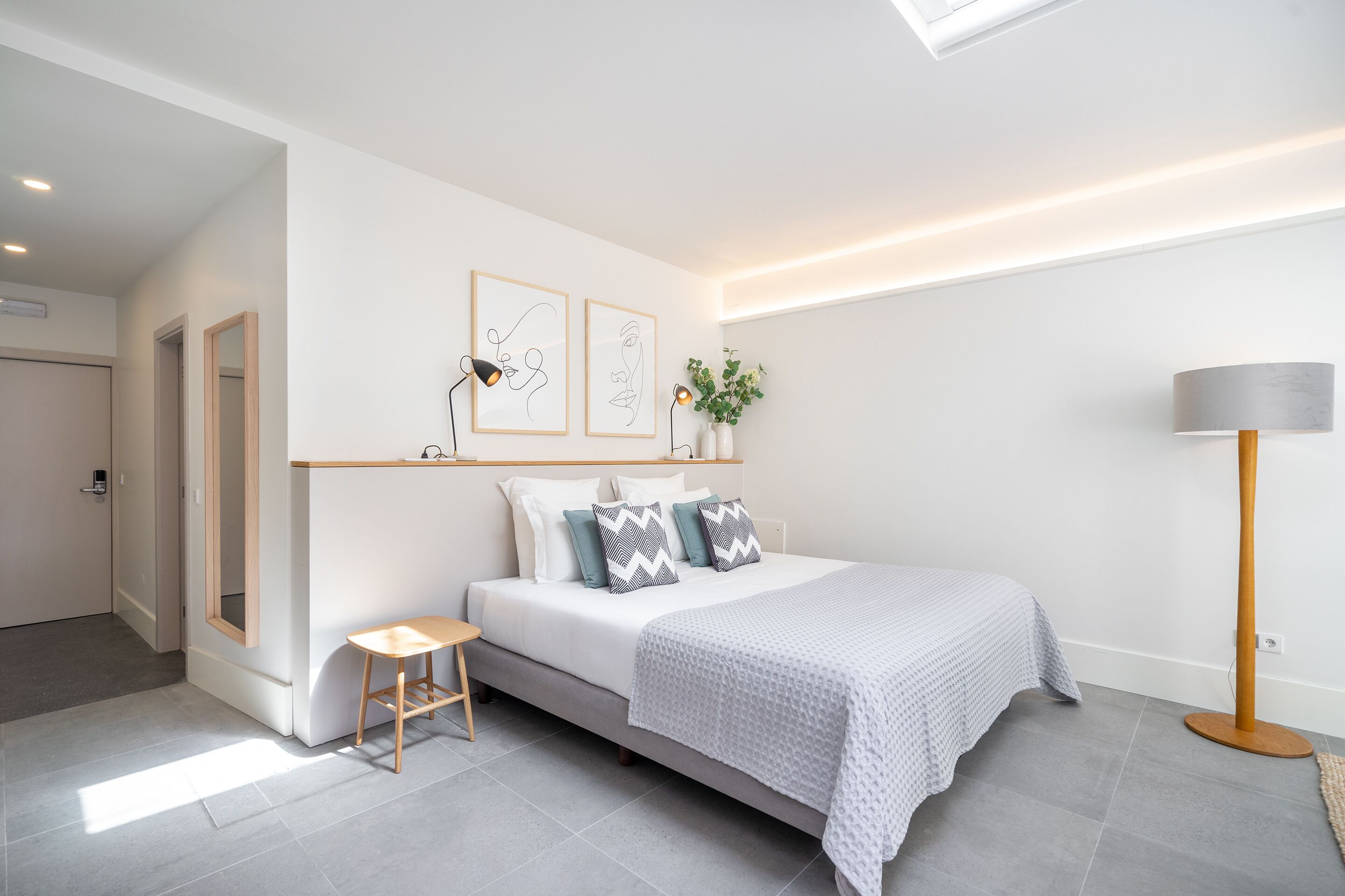 A modern bedroom with a bed, bedside table, and a floor lamp.