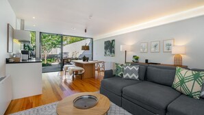 A modern living room with a grey sofa, a wooden coffee table, and a dining area with a table and chairs. - Canto de Luz (Porto)