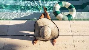 A person relaxing by a pool with a green and white inflatable ring. - Canto de Luz (Porto)