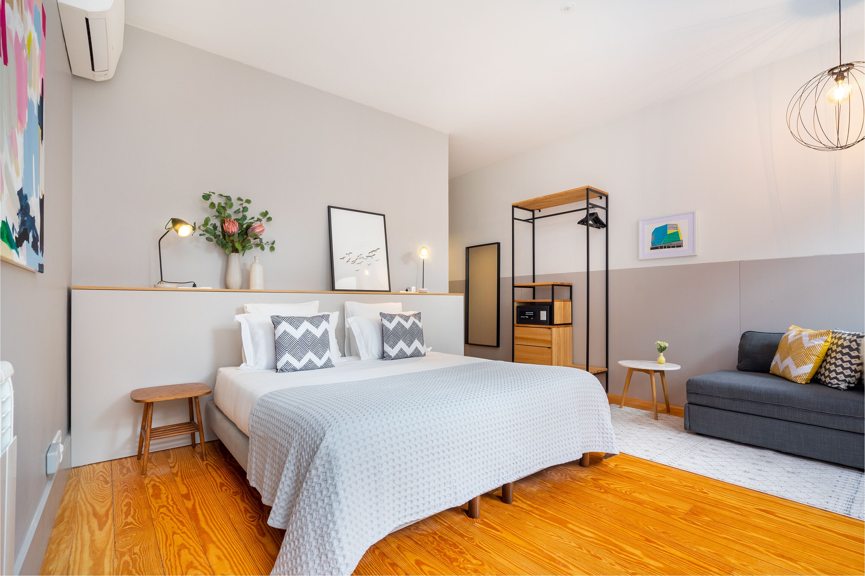 Une chambre moderne avec un grand lit, des tables de chevet, un canapé et une petite table avec une lampe.