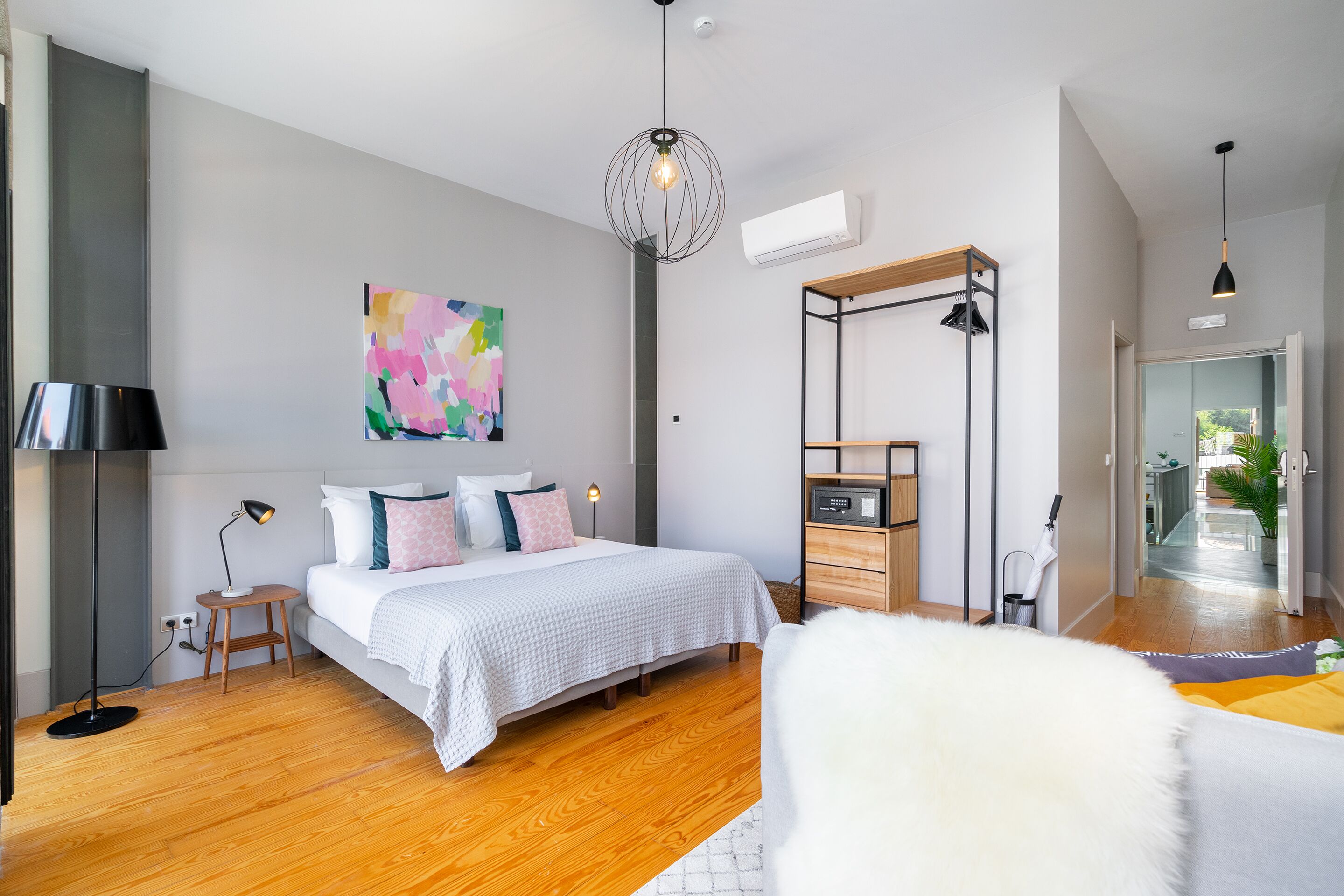 A modern bedroom with a bed, bedside table, lamp, and artwork on the wall.