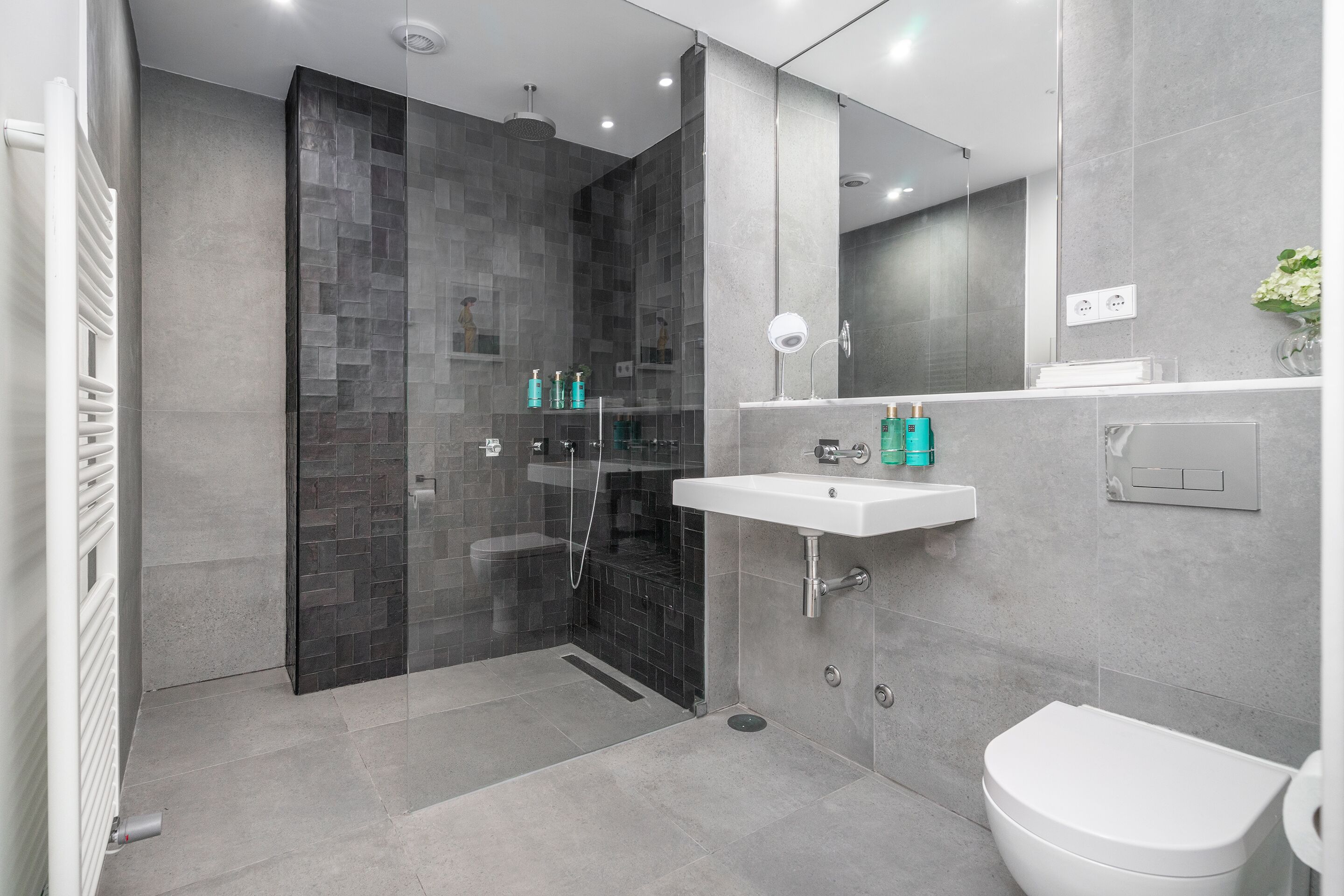 A modern bathroom with a glass-enclosed shower, a white sink, and a toilet.