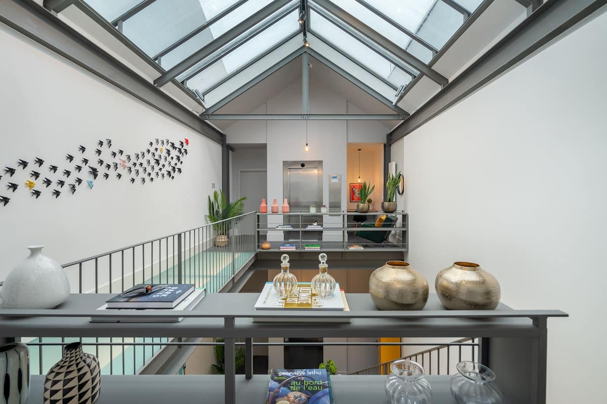 A modern interior with a glass ceiling, a staircase, and a wall with decorative items.