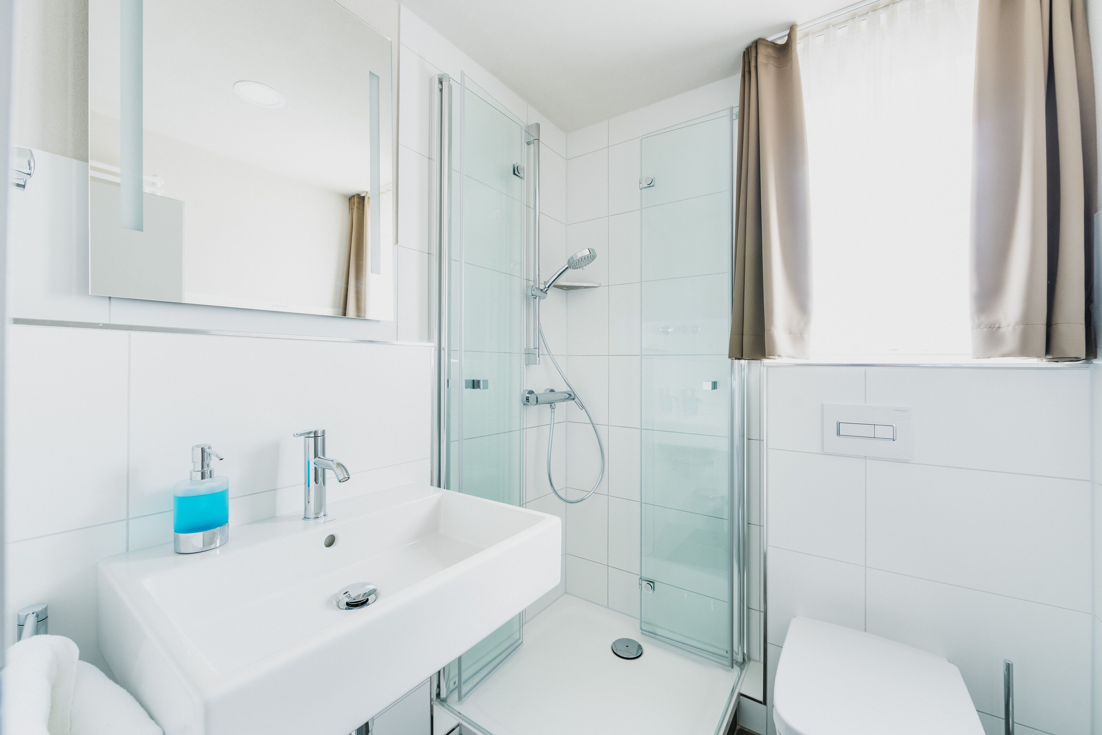 Une salle de bain moderne avec une douche à parois de verre, un lavabo blanc et des toilettes.