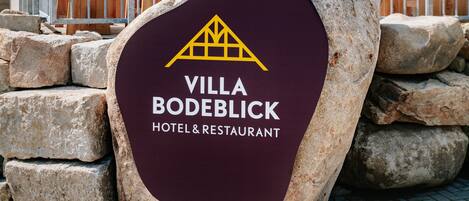 A sign for Villa Bodeblick Hotel & Restaurant with a mountain logo.