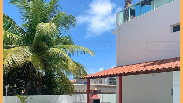 A swimming pool with a tiled deck, surrounded by lounge chairs and a covered patio area with green plastic chairs. - RENT apartments in Porto de Galinhas, fully equipped and new! (Porto de Galinhas)