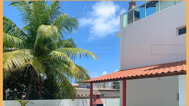 A swimming pool with a tiled deck, surrounded by lounge chairs and a covered patio area with green plastic chairs. - RENT apartments in Porto de Galinhas, fully equipped and new! (Porto de Galinhas)