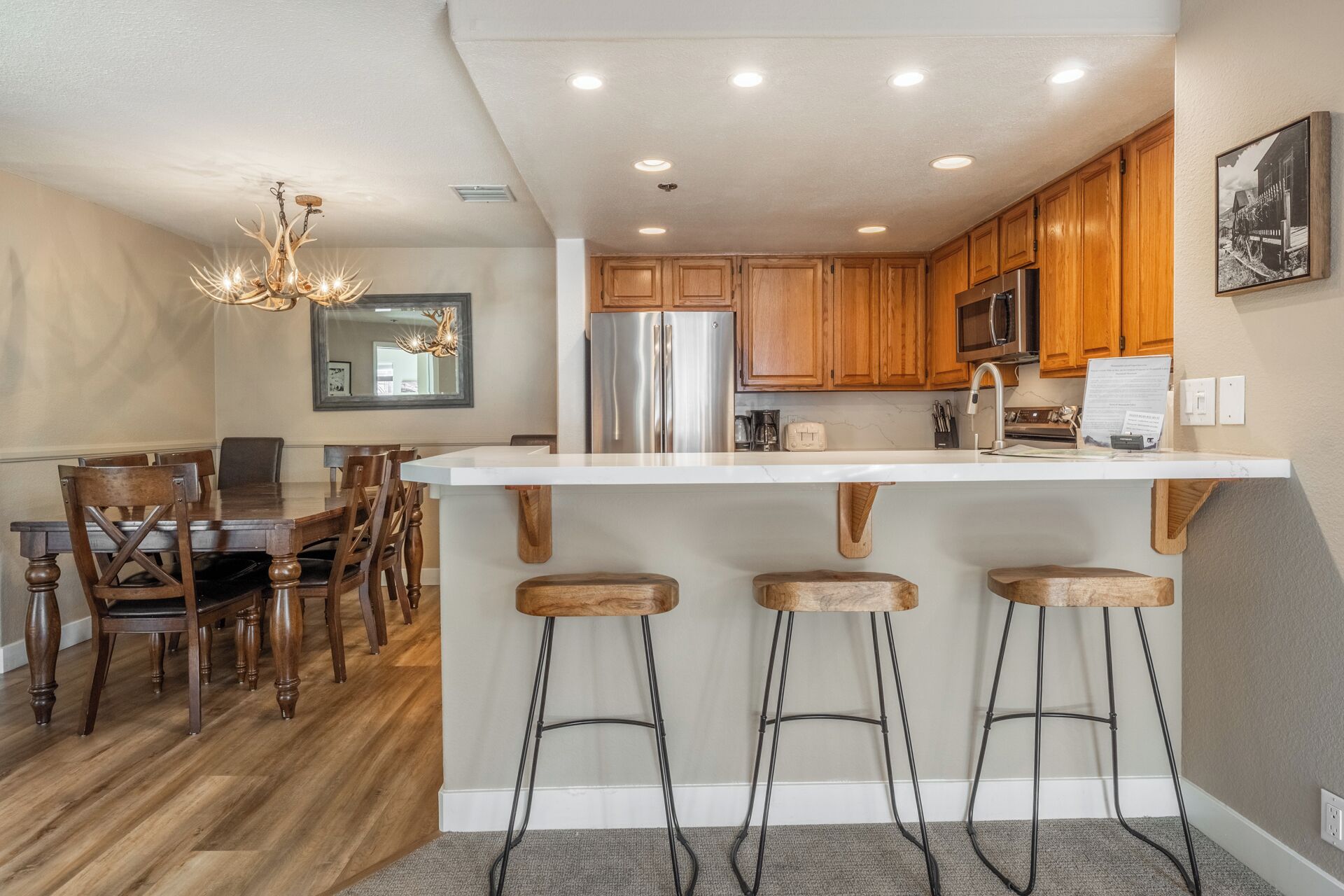A modern kitchen with wooden cabinets, stainless steel appliances, and a bar area with stools.