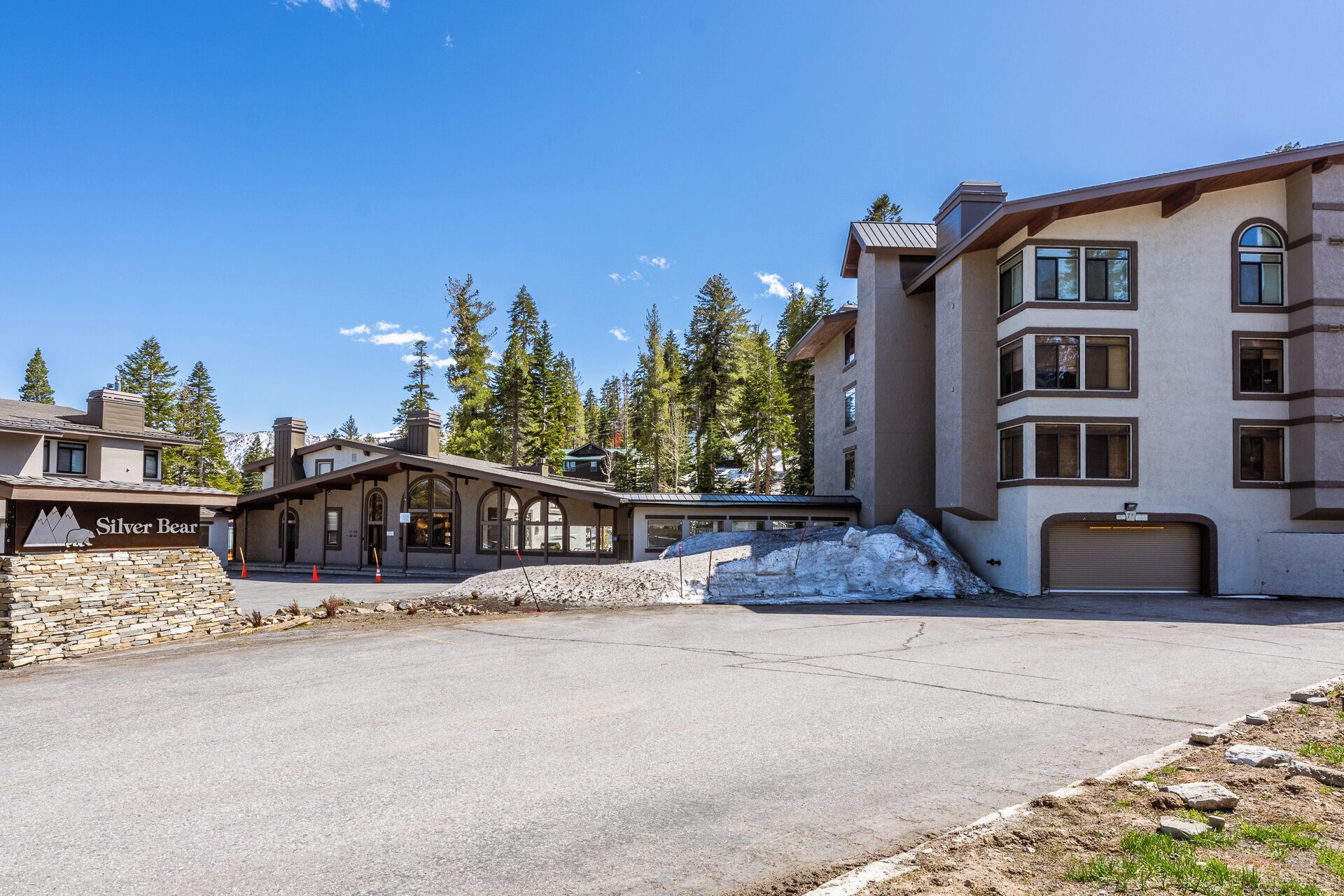 A hotel with a stone facade, multiple windows, and a parking area.