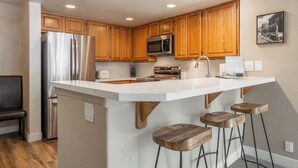 A modern kitchen with wooden cabinets, stainless steel appliances, and a large island with bar stools.